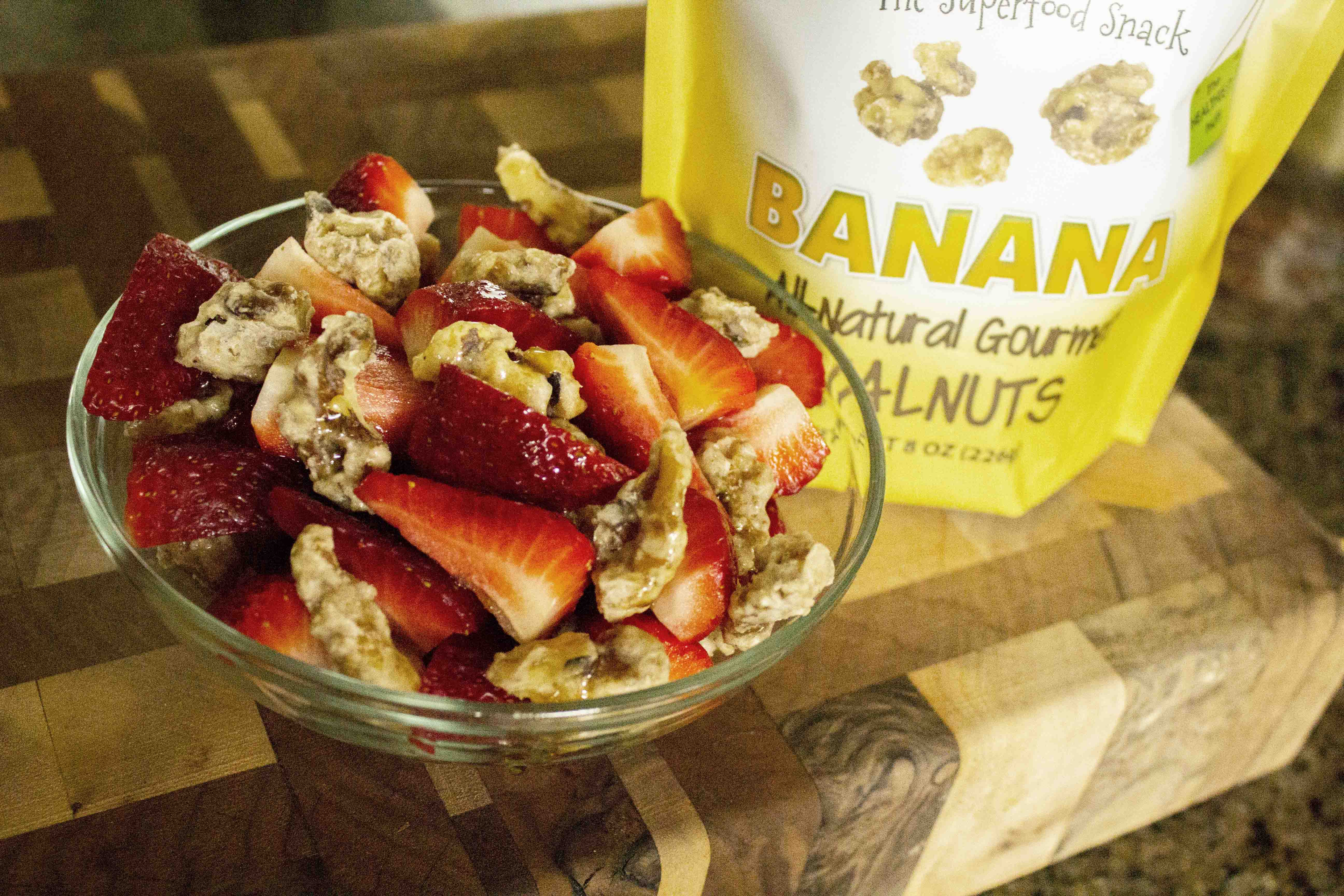 A bag of banana walnuts with a bowl of strawberries