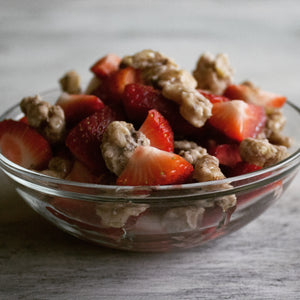 A bowl of strawberries mixed with banana coated walnut snacks