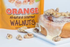 Close up of a cinnamon roll with orange coated walnut snacks