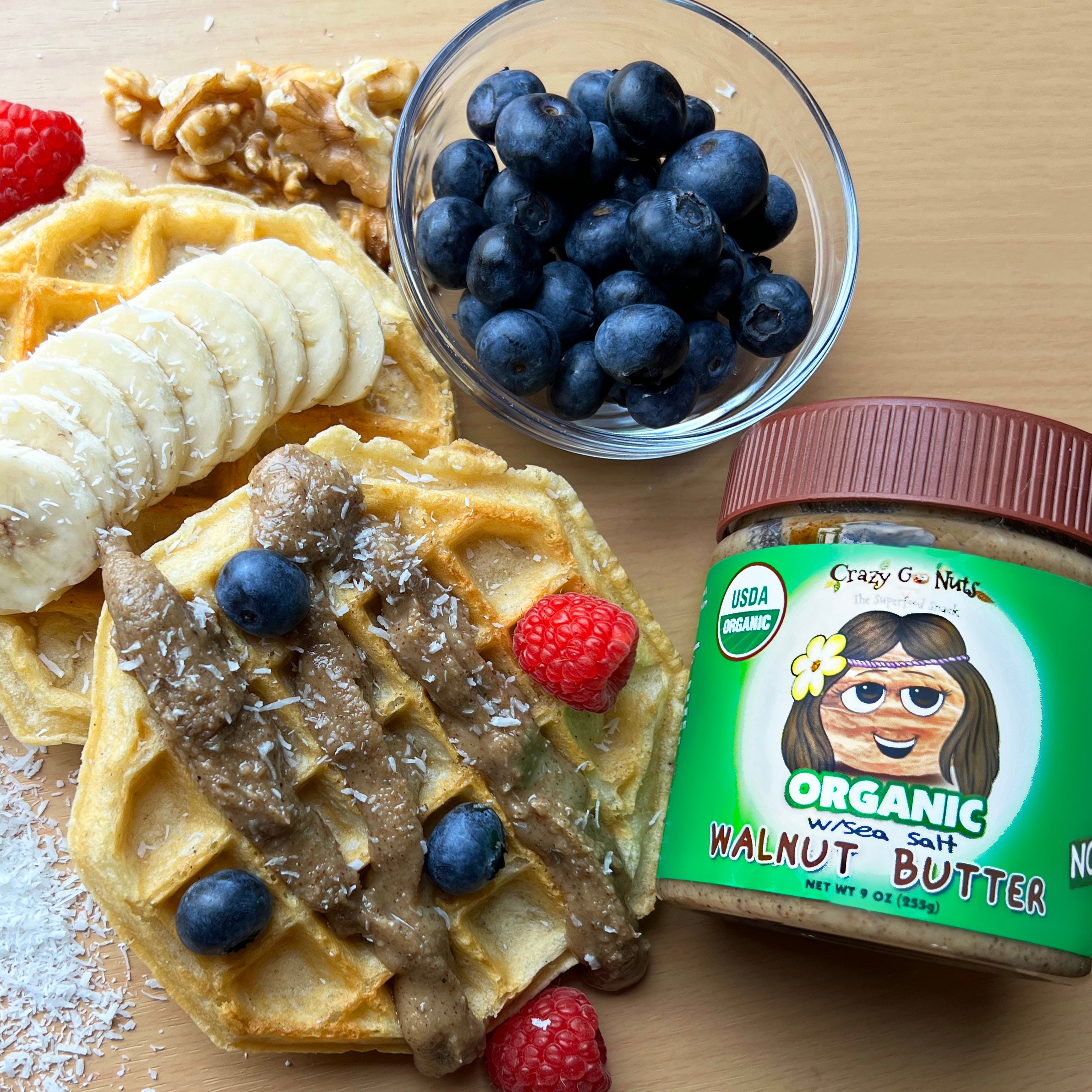 A jar of organic walnut butter with a waffle and fresh fruit