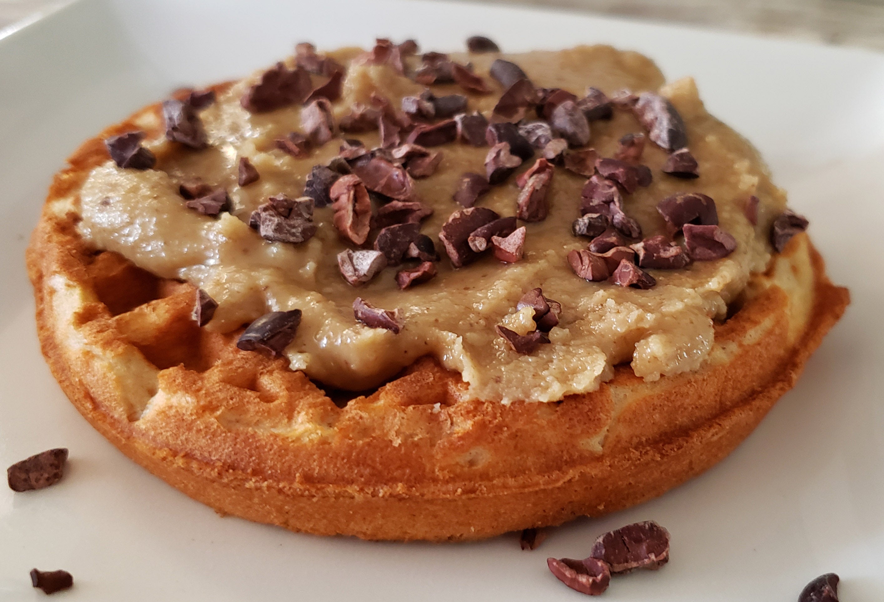 A waffle coated with maple walnut butter and cacao nibs